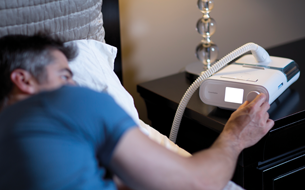 un homme allong&eacute; dans son lit utilisant un t&eacute;l&eacute;phone