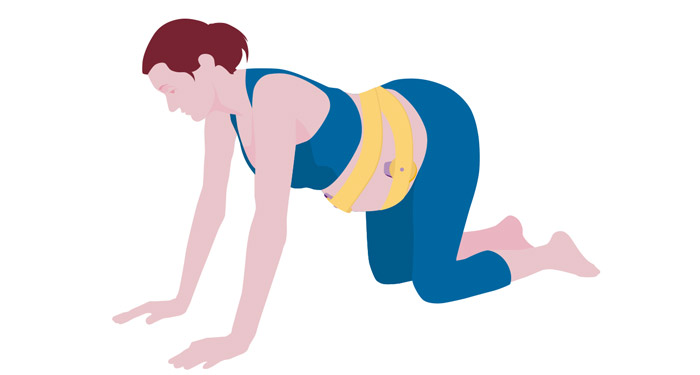 une femme en pantalon bleu et un haut bleu avec une ceinture jaune autour du ventre