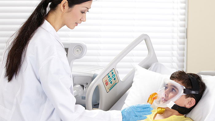 Une clinicienne place un masque respiratoire sur le visage d&rsquo;un enfant