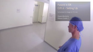Vivez l&rsquo;exp&eacute;rience Google Glass &ndash; un m&eacute;decin marche dans un couloir et les param&egrave;tres vitaux d&rsquo;un patient sont affich&eacute;s dans le coin sup&eacute;rieur droit.