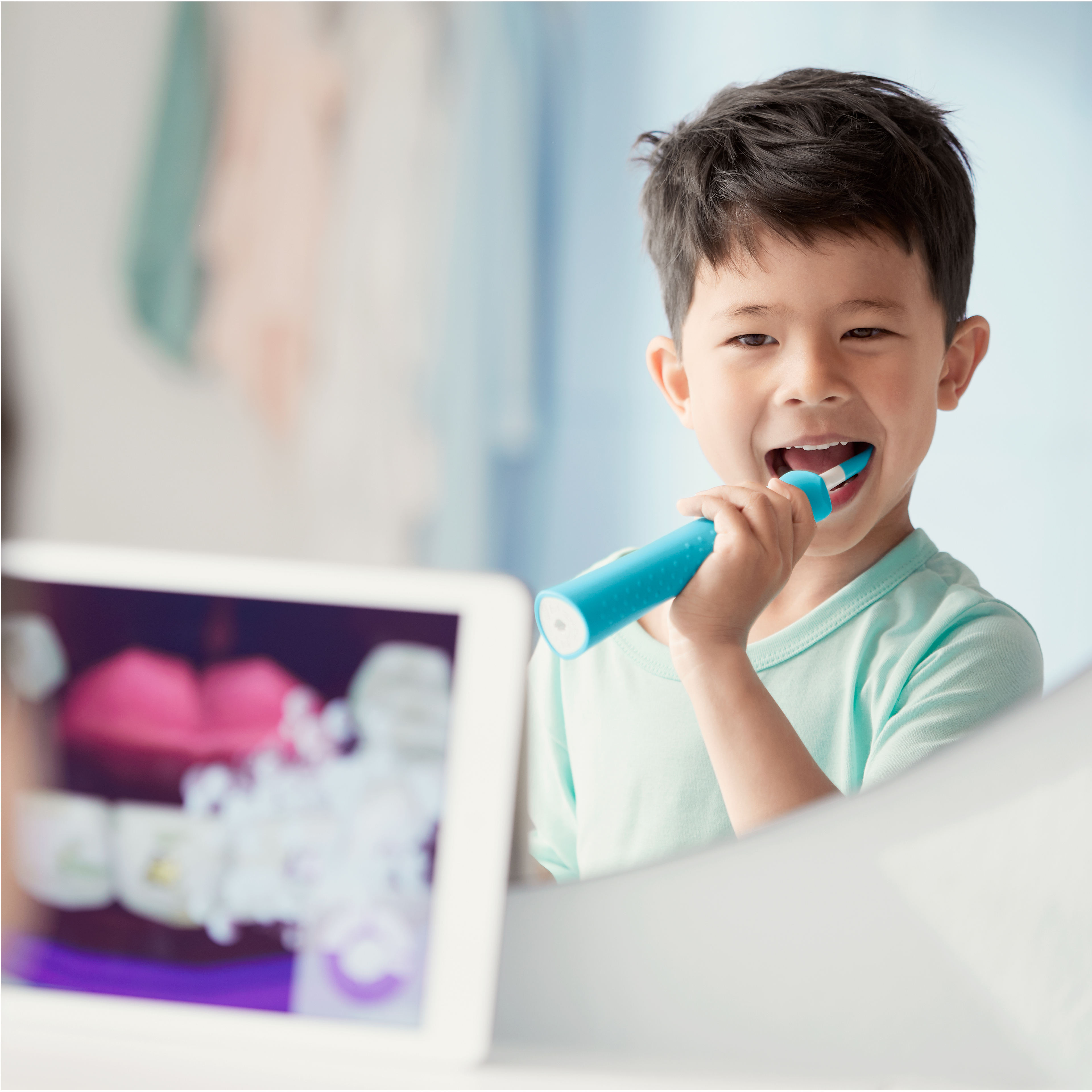 Gar&ccedil;on utilisant une brosse &agrave; dents &eacute;lectrique Sonicare for Kids tout en regardant l'application Sonicare for Kids