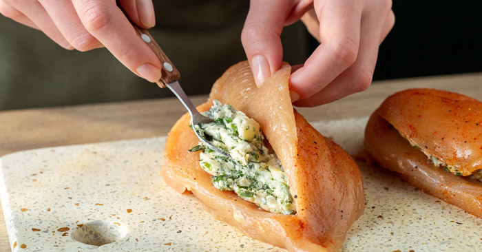 Utilisez une c. &agrave; caf&eacute; pour farcir chaque poche des filets de poulet avec une quantit&eacute; &eacute;gale de beurre aux herbes.