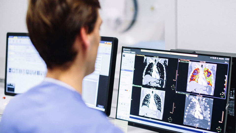Photo d&rsquo;un manipulateur examinant des images cliniques de TDM sur un &eacute;cran