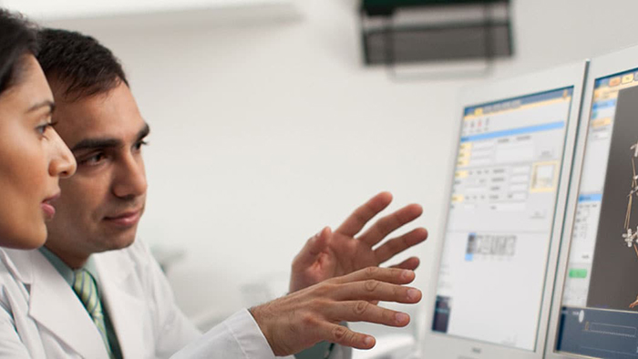 Photo de cliniciens qui se concertent &agrave; propos de r&eacute;sultats TDM sur un &eacute;cran d&rsquo;ordinateur