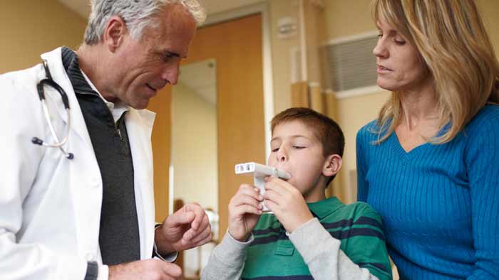 professionnel de sant&eacute; aidant un enfant avec un appareil de gestion de l'asthme