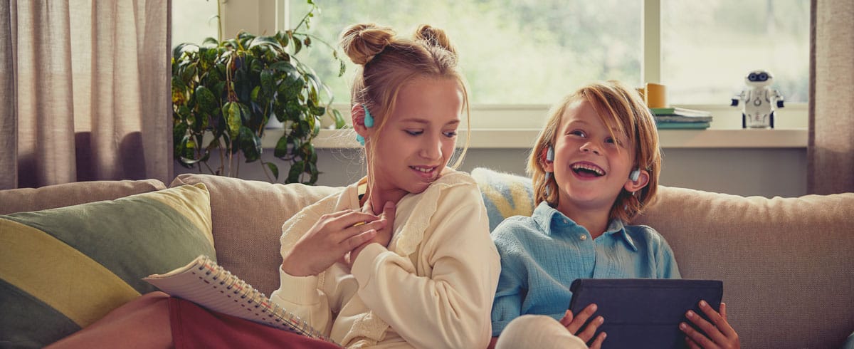 Enfants portant des casques pour enfants open-ear Philips et regardant une vid&eacute;o