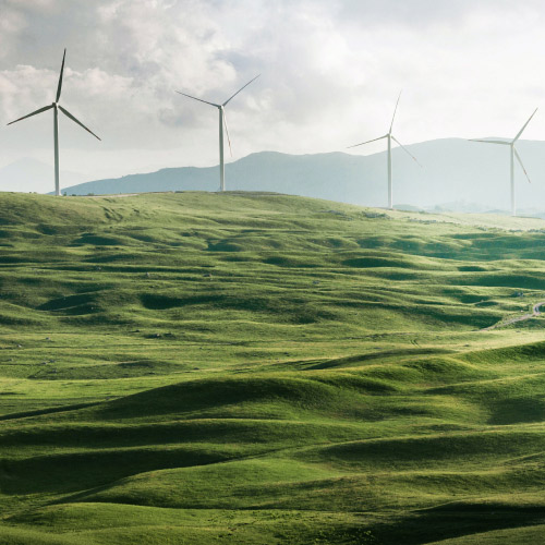 Centrale &eacute;olienne sur des collines, symbolisant les &eacute;nergies renouvelables et le d&eacute;veloppement durable en entreprise.